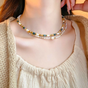 Detail of layered freshwater pearl necklace with colorful beads on a beige knit sweater
