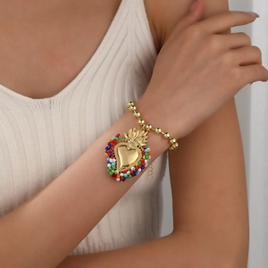 Nahaufnahme eines goldenen Perlenarmbands mit Herzanhänger getragen von einem Model