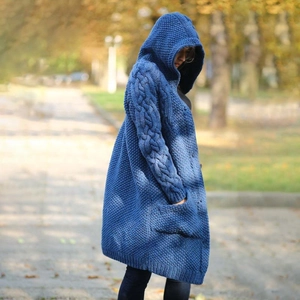 Dettaglio della maglia a trecce e tasca grande su un cardigan blu con cappuccio