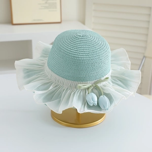 Detail of mint green woven straw hat with white chiffon ruffle and tulip bow charms