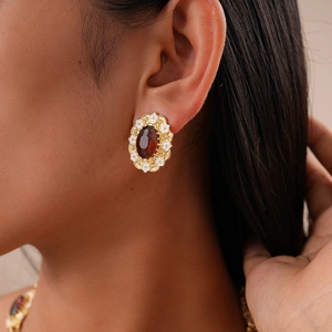 Close-up of vintage oval earring with amber gemstone and floral enamel details on model