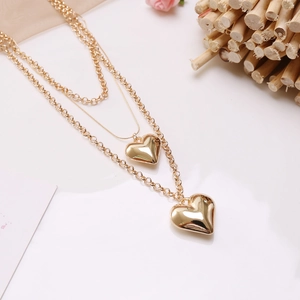 Detail shot of golden double layered heart pendant necklace with elegant rose decor