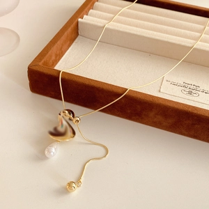 Detail of tiger eye cross pendant with gold chain and white pearl on velvet box