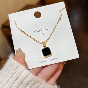 Minimalist gold plated titanium necklace with square black pendant on white card
