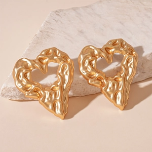 Macro detail of gold heart earrings featuring unique molten lava texture on stone surface