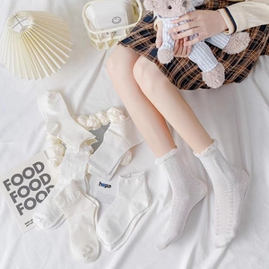Chaussettes blanches en coton à volants pour femmes en plusieurs styles sur un lit blanc