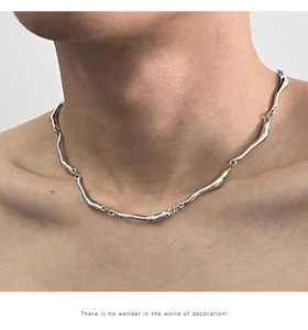 Close-up of irregular wavy silver chain necklace showing liquid metal texture on neck