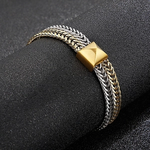 Macro detail of two-tone woven dragon bone chain with gold square pyramid clasp