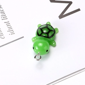 Detailed close-up of a green resin turtle pendant with realistic shell patterns and metal ring