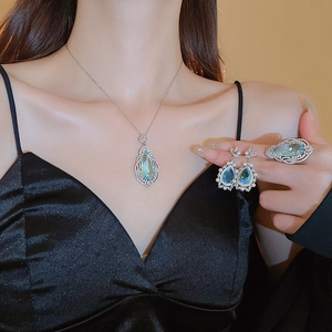 Close-up of elegant blue teardrop gemstone jewelry set on model with pearl necklace