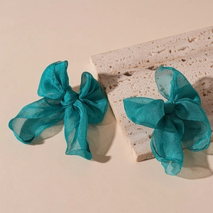 Detail view of two teal organza lace bow earrings with elegant semi-transparent texture