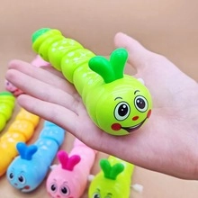 Handheld detail of a green wind-up caterpillar toy with a smooth plastic finish