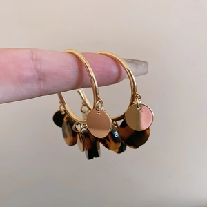 Detailed macro view of vintage leopard print acetate and gold metal disc drop earrings