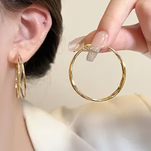 Detailed view of large gold hoop earrings with polished finish and secure pin closure