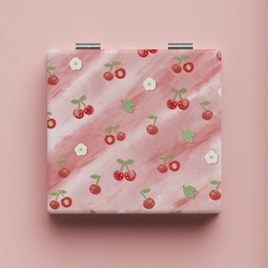 Close-up of portable makeup mirror featuring red cherry patterns and metal hinges