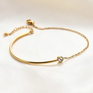 Detail of 18K gold-plated stainless steel bracelet with C-shape tube and inset zircon