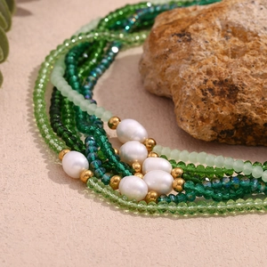 Detail of green crystal beads and freshwater pearls on a stainless steel necklace