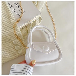 Mini white jelly bag with gold chain strap held against a beige knit background