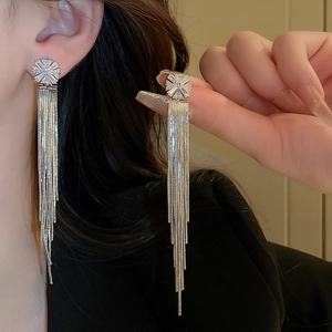 Elegant silver tassel earrings with zircon flower studs shown on hand and model