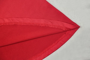 Detail of precise hem stitching and smooth red fabric texture on a long-sleeve A-line dress