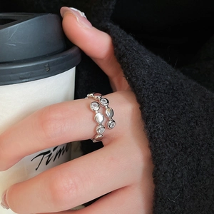 Detailed view of silver layered ring with zircon inlay worn on hand with coffee cup