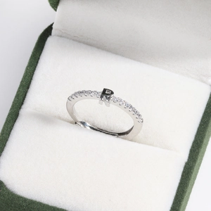 Macro view of silver adjustable ring with crystal-encrusted letter R in a green box