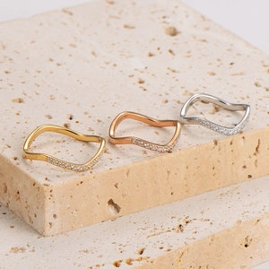 Three-color wavy stainless steel rings set with micro-paved cubic zirconia on travertine