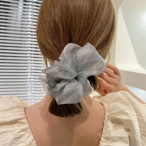Macro detail of a silver grey organza scrunchie styled on a elegant low ponytail