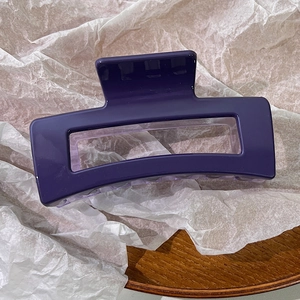 Close-up of a large purple resin hair claw clip with a hollow rectangular design