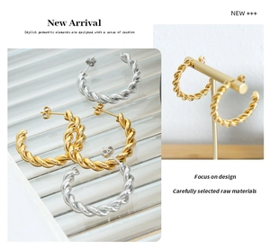 Macro detail of thick twisted rope C-shaped earrings in polished gold and silver finishes