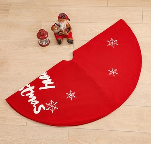 Detail of red Christmas tree skirt with white Merry Christmas text and snowflake patterns