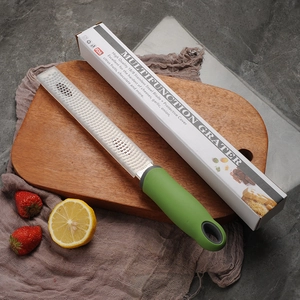 Stainless steel cheese and lemon zester with a green handle and protective cover on a board