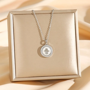 Collier avec pendentif rond Main de Fatma en argent et zircons sur boîte à bijoux
