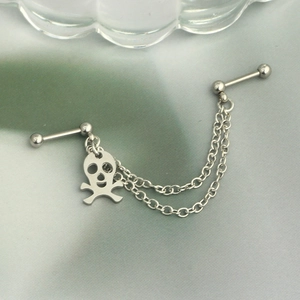 Detail of stainless steel double piercing earring with chain and skull pendant charm