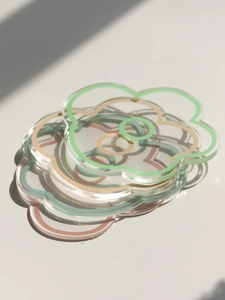 Macro shot of stacked flower-shaped acrylic coasters with colorful edges and shadows