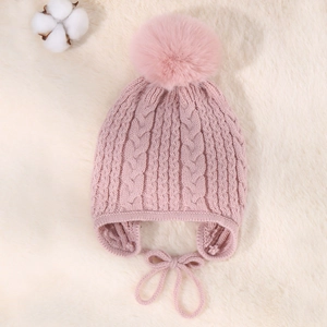 Detail view of pink cable knit baby winter hat with soft pompom and earflap straps
