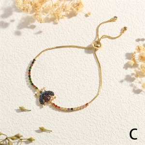 Detail of adjustable gold-tone insect bracelet with colorful zircon beetle charm