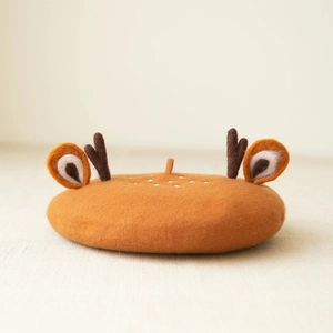 Detail showing plush brown beret with 3D reindeer antlers and soft wool texture