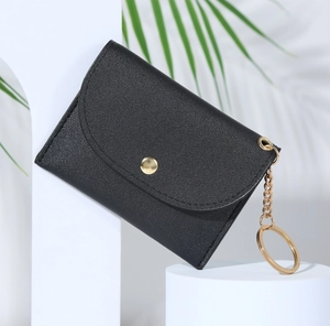 Gros plan du porte-cartes enveloppe en cuir noir avec porte-clés doré et décor géométrique