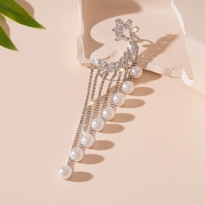 Détail du clip d'oreille argenté avec zircons et perles d'imitation sur un décor minéral