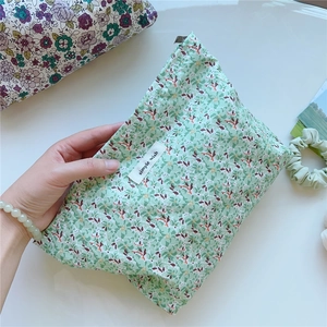Close-up of floral cotton cosmetic bag with 'simple wish' label on white desk