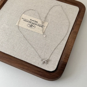 Detail showing the S925 sterling silver stamp on an elegant bow pendant necklace