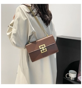 Détail d'un sac bandoulière marron en similicuir mat avec boucle géométrique dorée et chaîne