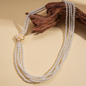 Dettaglio collana di perle multistrato con pendente floreale in resina su ramo di legno