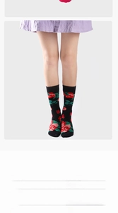 Detailed view of floral mid-calf socks with red roses and green leaves on black fabric