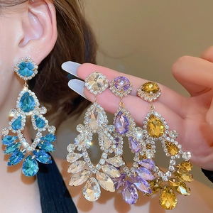 Macro detail of luxury teardrop fringe earrings with crystal stones and silver needles