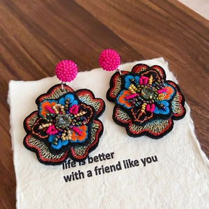 Detailed close-up of handmade ethnic floral earrings with colorful embroidery and beads