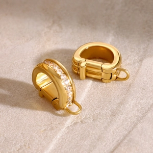 Macro shot of gold D-shape buckle with pavé white zircons on stone background