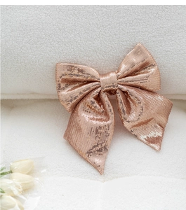 Detail shot of a rose gold sequin Christmas bow on a white textured fleece background