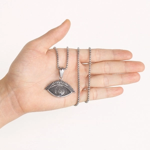 Detailed view of vintage silver eye pendant with dot textures held in palm